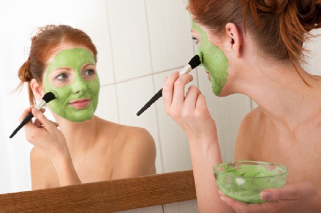 Body care series - Young woman applying facial mask